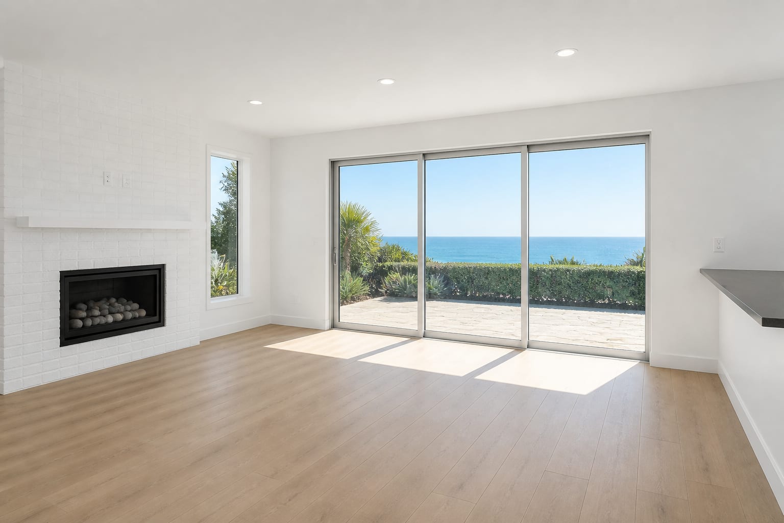 Empty living room looking toward a white brick fireplace and the hedge beyond