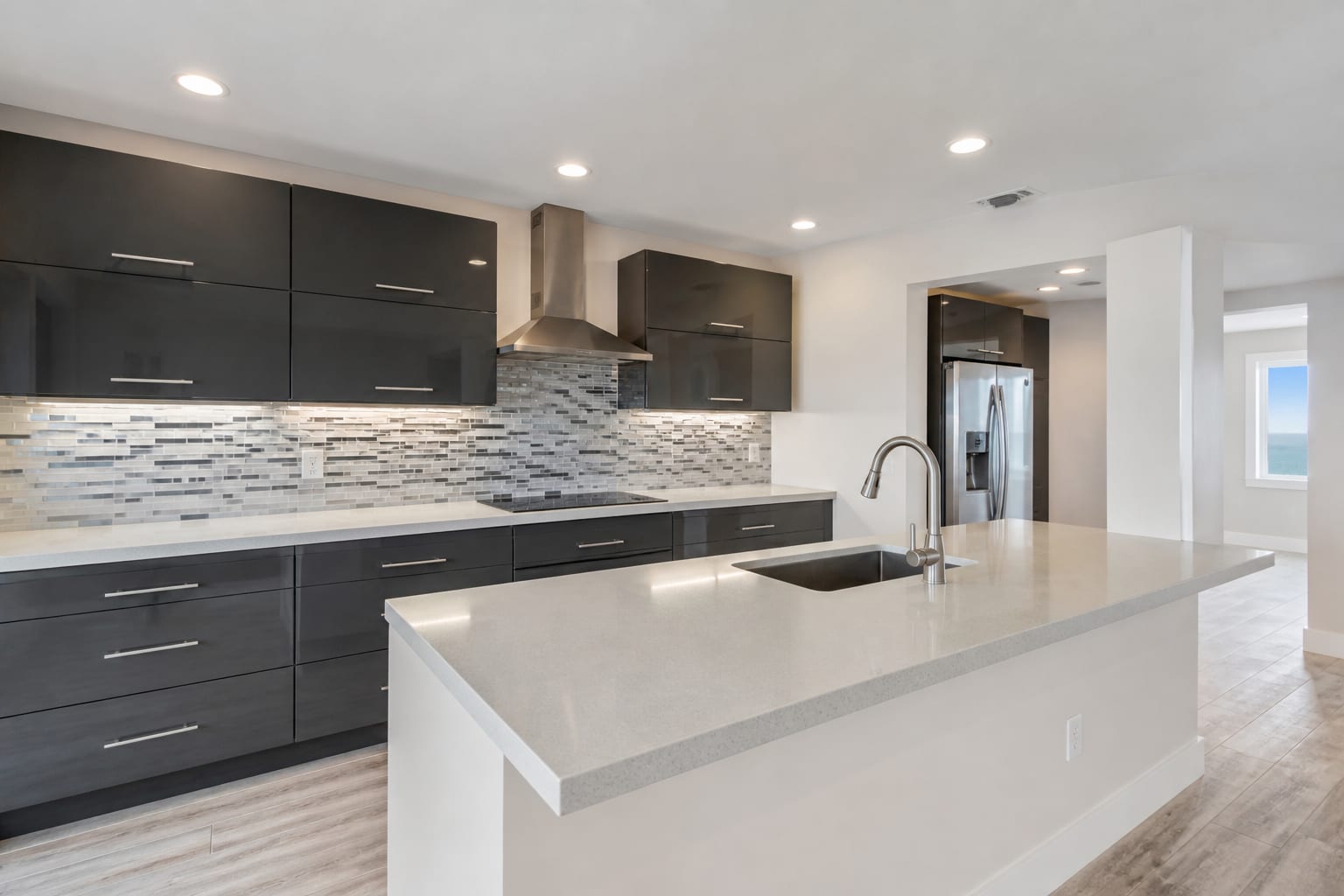 Kitchen peninsula with charcoal cabinets and a quartz counter